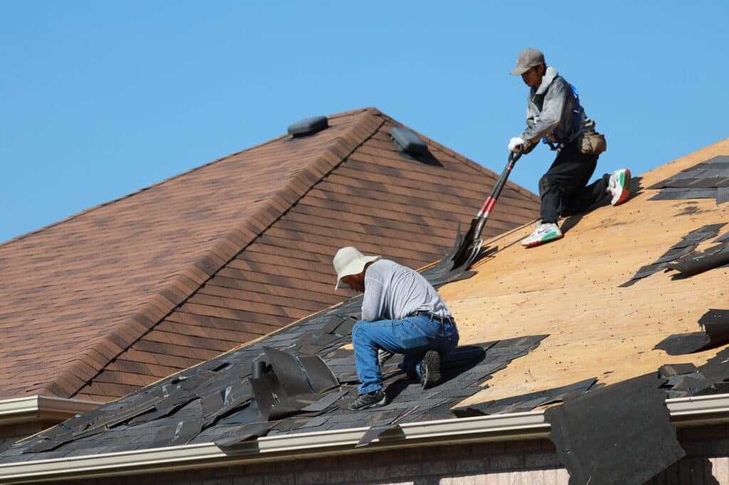 Removal of old shingles from a roof by roofers